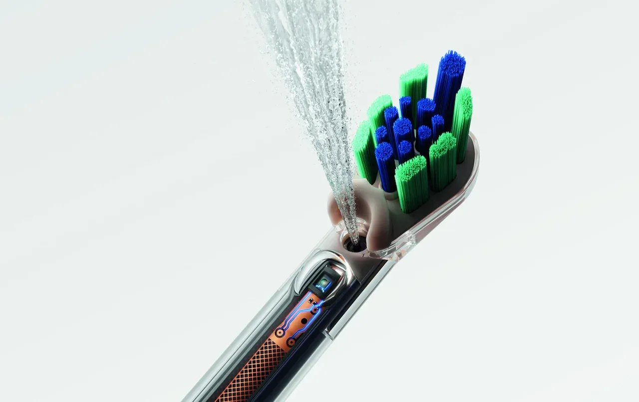 Close-up of the CameraJet head showing blue and green bristles, the embedded camera and a jet of liquid firing